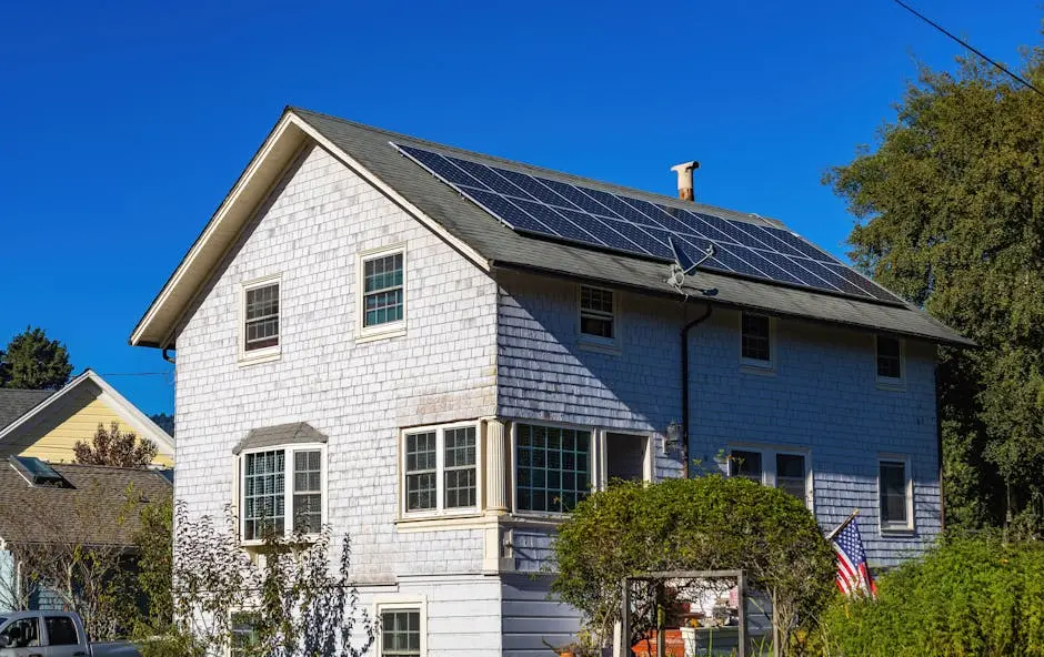 A modern two-story home with solar panels on its roof under a clear blue sky.