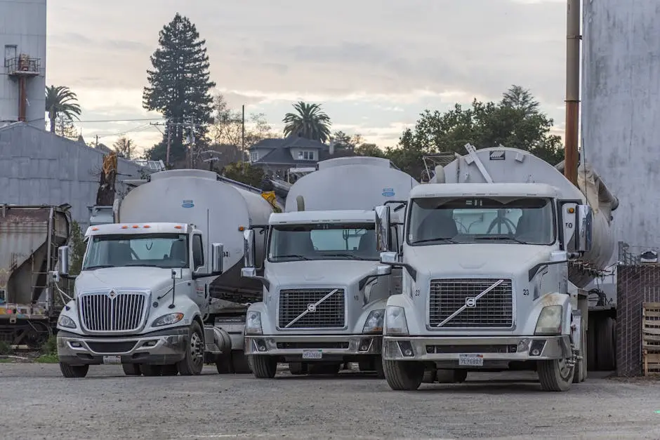 A row of white trucks parked in an industrial factory setting. Ideal for transport and logistics themes.