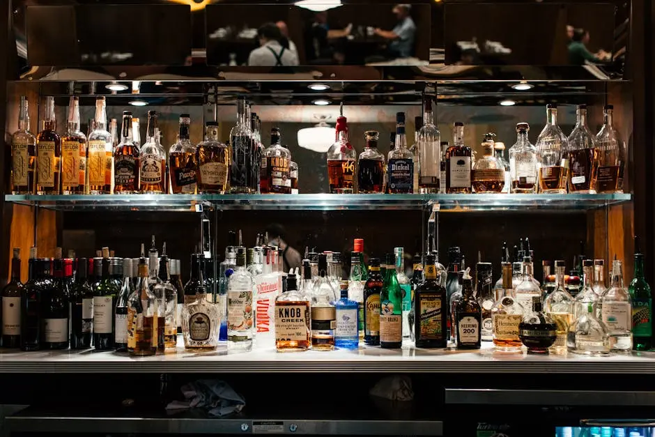 A diverse collection of liquor bottles showcased on a well-lit bar shelf.