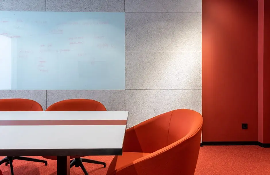 Stylish contemporary conference room with red chairs and whiteboard wall.