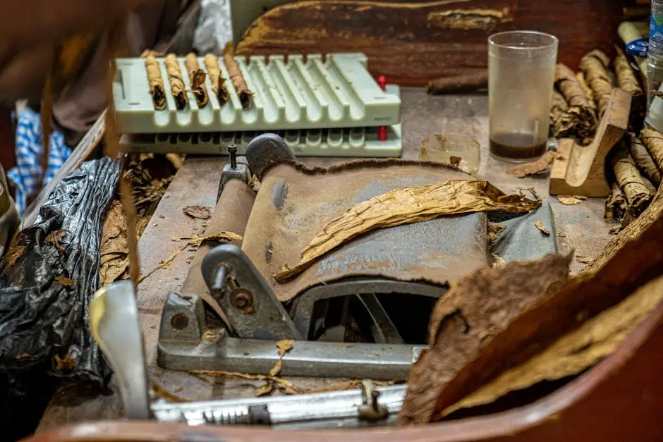 Close-up of a vintage tobacco rolling machine and cigars in a rustic workspace.