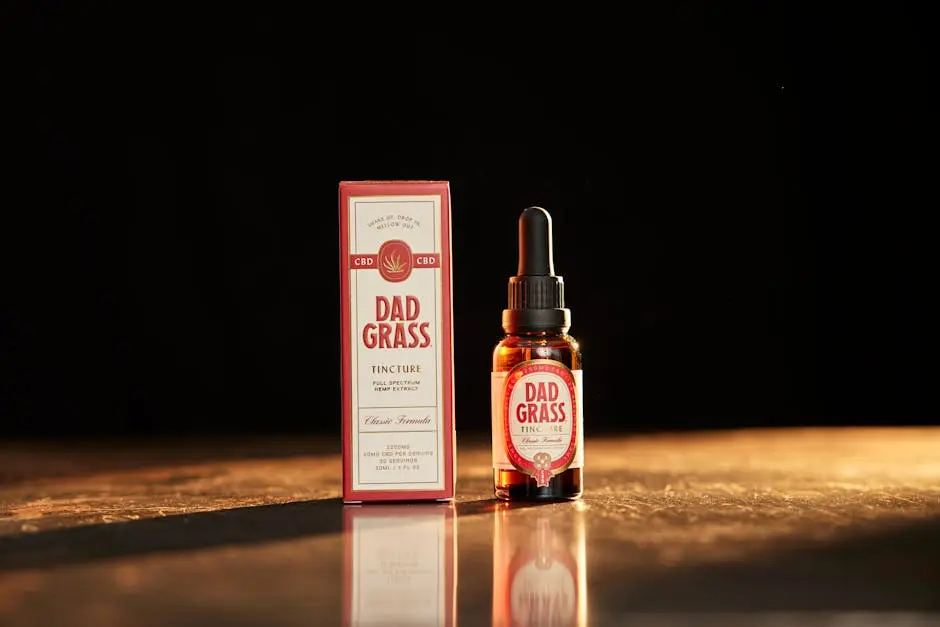 Close-up of Dad Grass full spectrum CBD tincture bottle and box on a warm wooden surface.