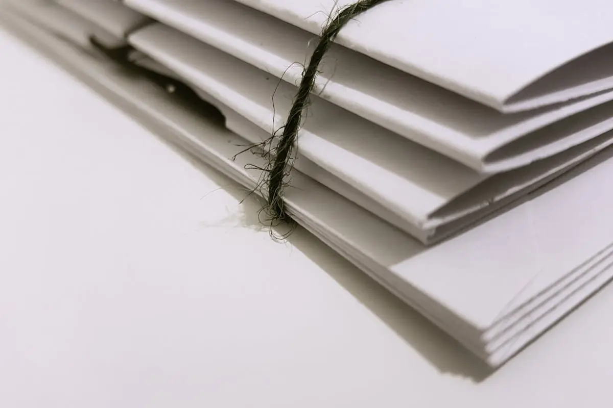 Pile of white envelopes tied with a green string, showcasing a minimalist design.