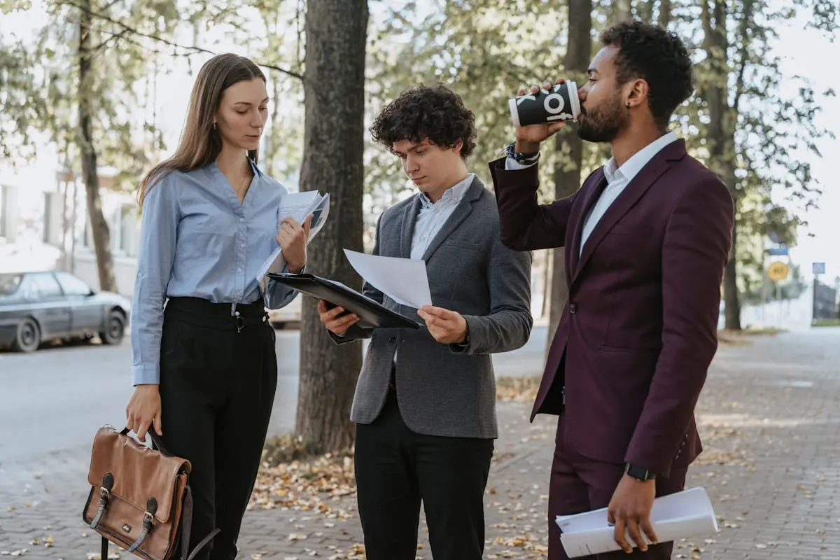 Group of professionals reviewing documents and drinking coffee on a city street.