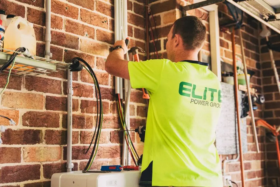 Electrician performing solar battery installation for sustainable energy storage in a home setting.
