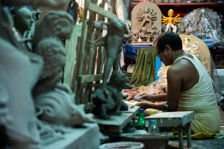 A skilled craftsman shapes intricate idols in a Kolkata workshop. Traditional artistry in action.