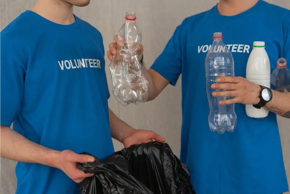 Two volunteers in blue shirts collect plastic bottles for recycling, showcasing community involvement.