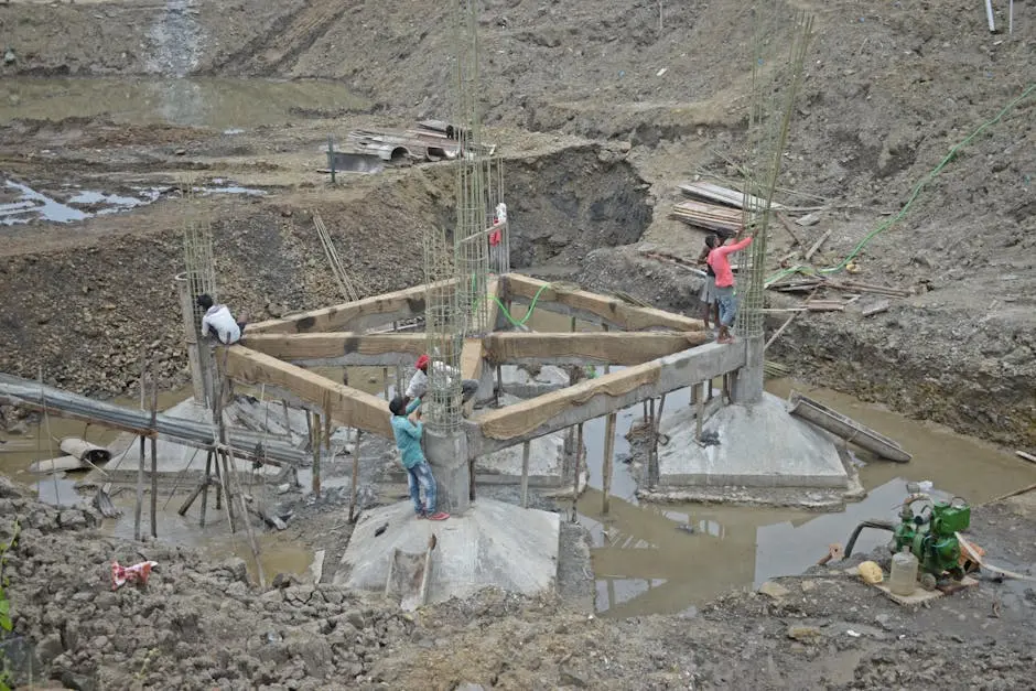 Workers constructing a building foundation with rebar and wooden supports outdoors.