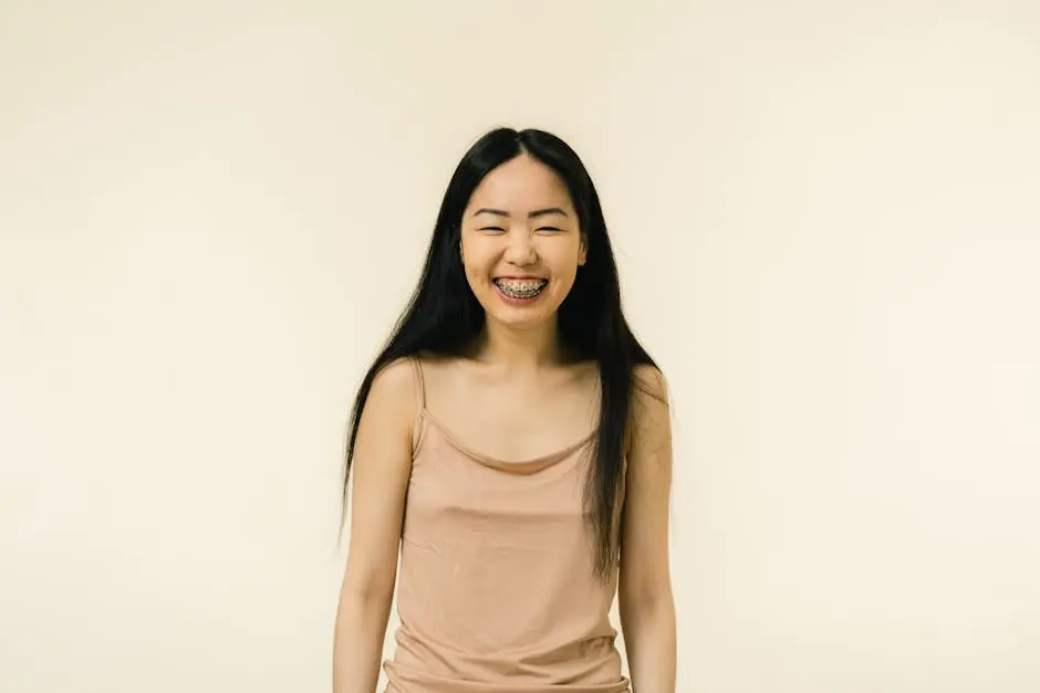 A cheerful young Asian woman with braces smiling in a studio setting.