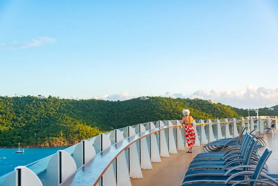 Senior woman enjoying a serene view from a cruise ship deck, surrounded by lush hills and ocean.