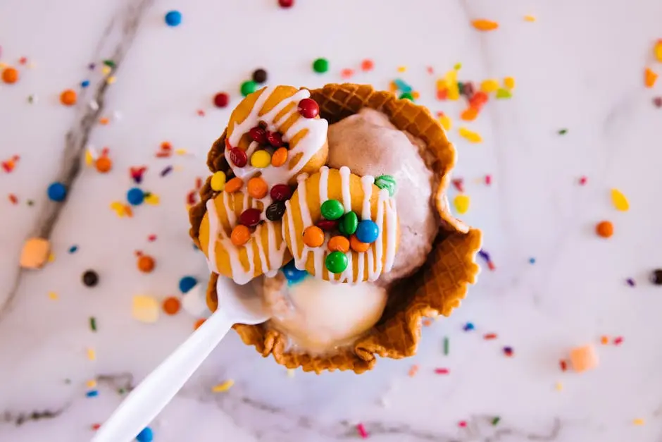 Delicious ice cream in a waffle bowl topped with colorful candy and drizzled icing.