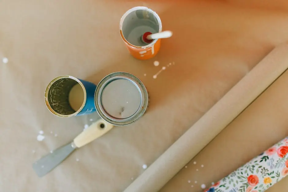Top view of paint cans, scraper, and wrapping paper on a brown surface.