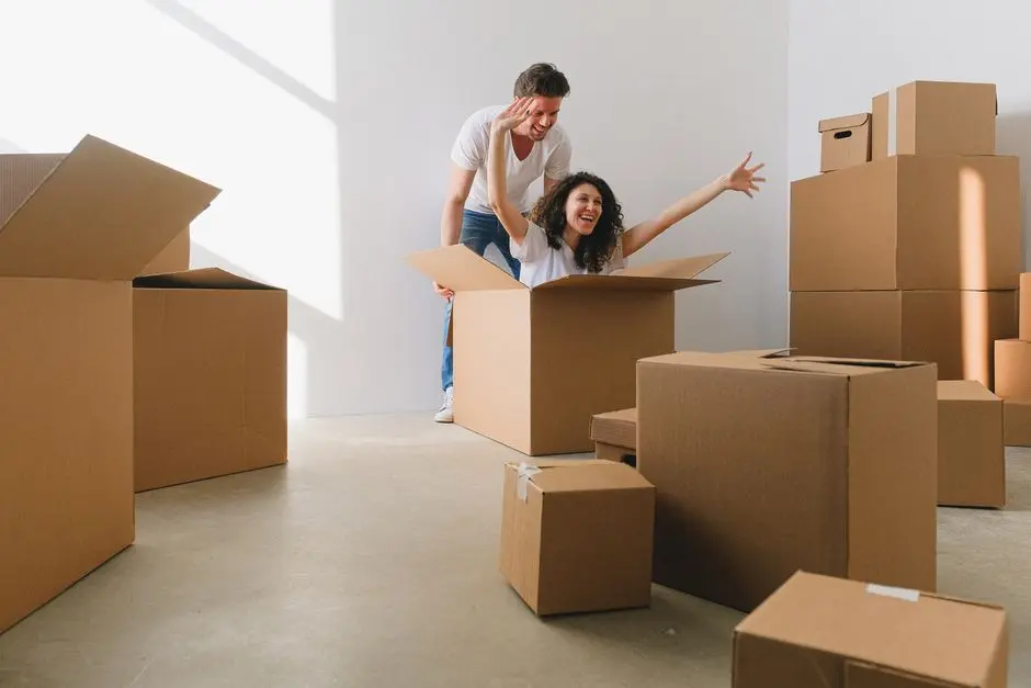 Joyful couple having fun with cardboard boxes during moving day in a bright room.