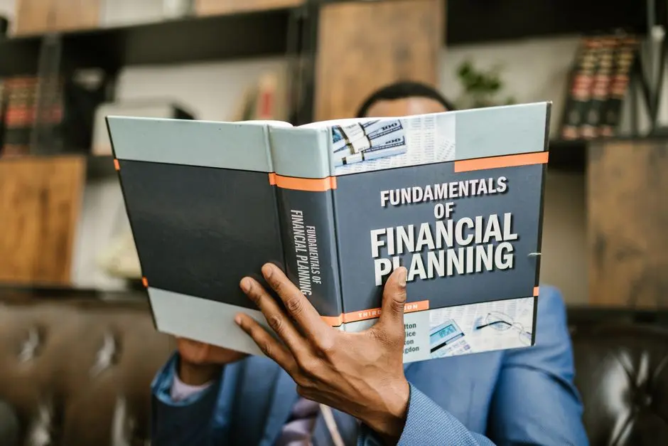 A professional individual in a suit reading ‘Fundamentals of Financial Planning’ indoors.