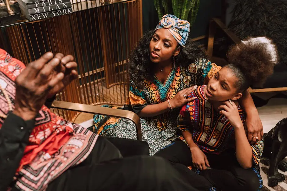 Two adults and a child in vibrant traditional clothing sharing a joyful moment indoors.