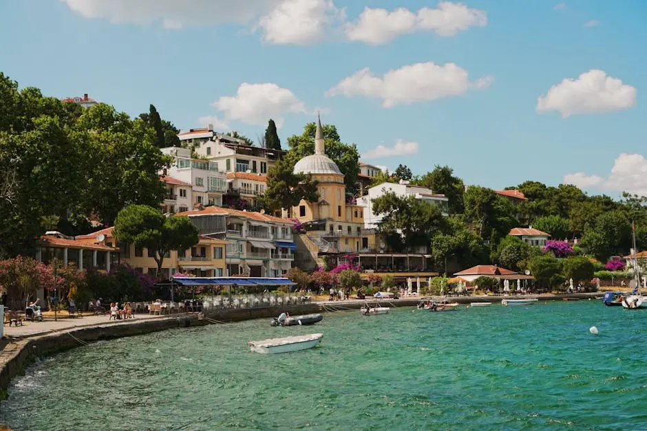 Charming waterfront village with boats, greenery, and colorful architecture under a bright blue sky.