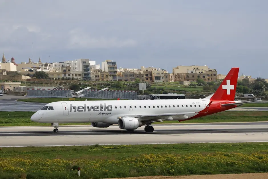 Helvetic Airways aircraft taxiing on runway with urban background.