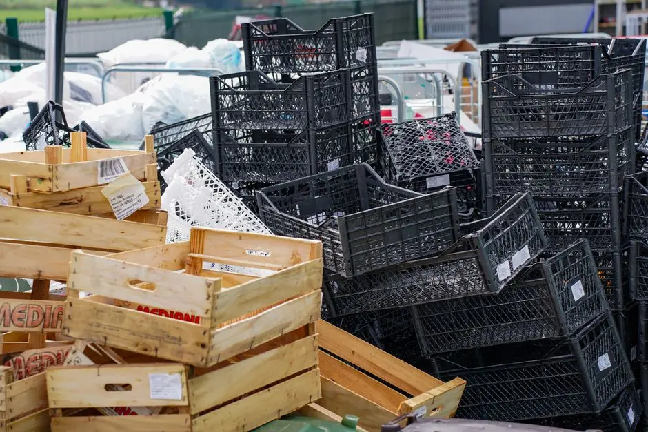 Pile of black plastic and wooden crates in an outdoor market setting.
