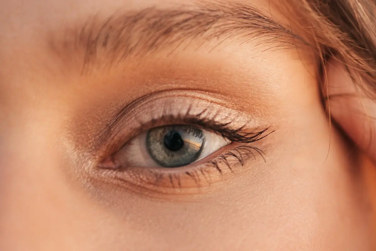 Detailed close-up of a human eye with visible eyelashes, skin texture, and natural lighting.