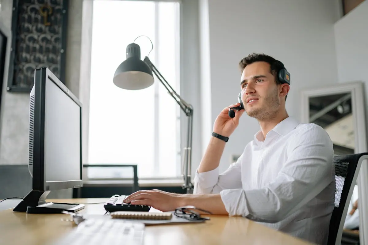 Male call center agent with headset working at desk, providing excellent customer service.