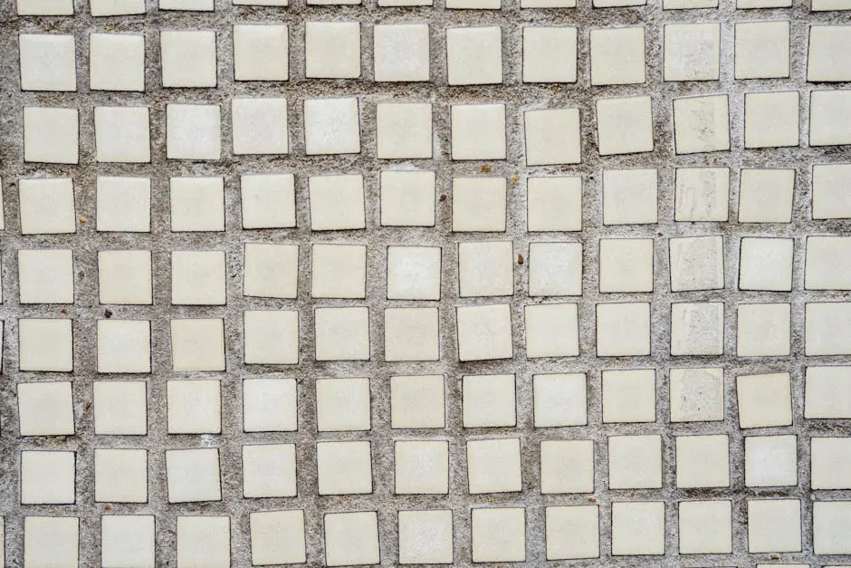 Close-up of a geometric square tile pattern on a textured concrete wall.
