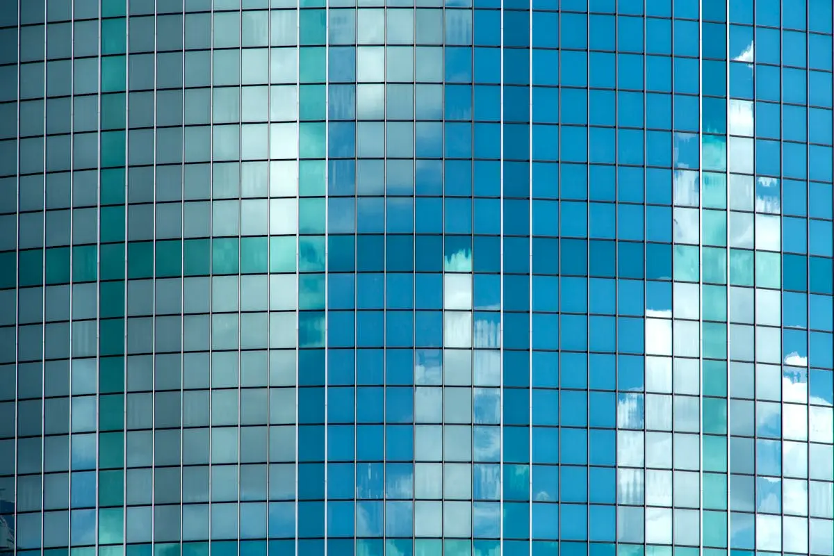 Curved glass facade reflecting clouds in a modern building, Rotterdam, Netherlands.