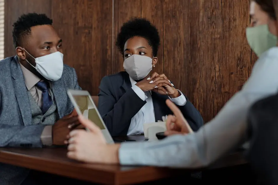 Diverse team discussing strategies while wearing face masks in a meeting room.