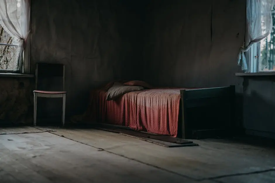 Moody, textured room with an old bed and wooden chair showcasing abandonment.