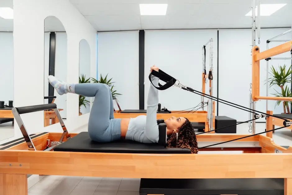Woman working out on a Pilates reformer in a modern, well-equipped gym for fitness and health.