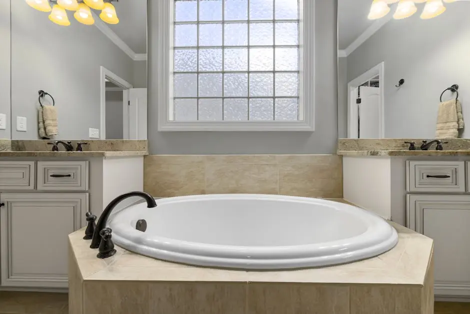 A luxurious bathroom featuring a marble bathtub, pristine cabinets, and elegant lighting.