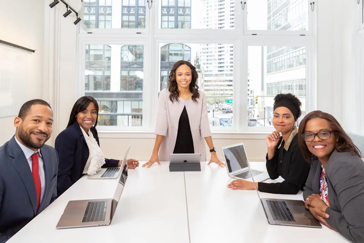 Multicultural business coach team collaborating in boardroom with laptops, showcasing teamwork and diversity.