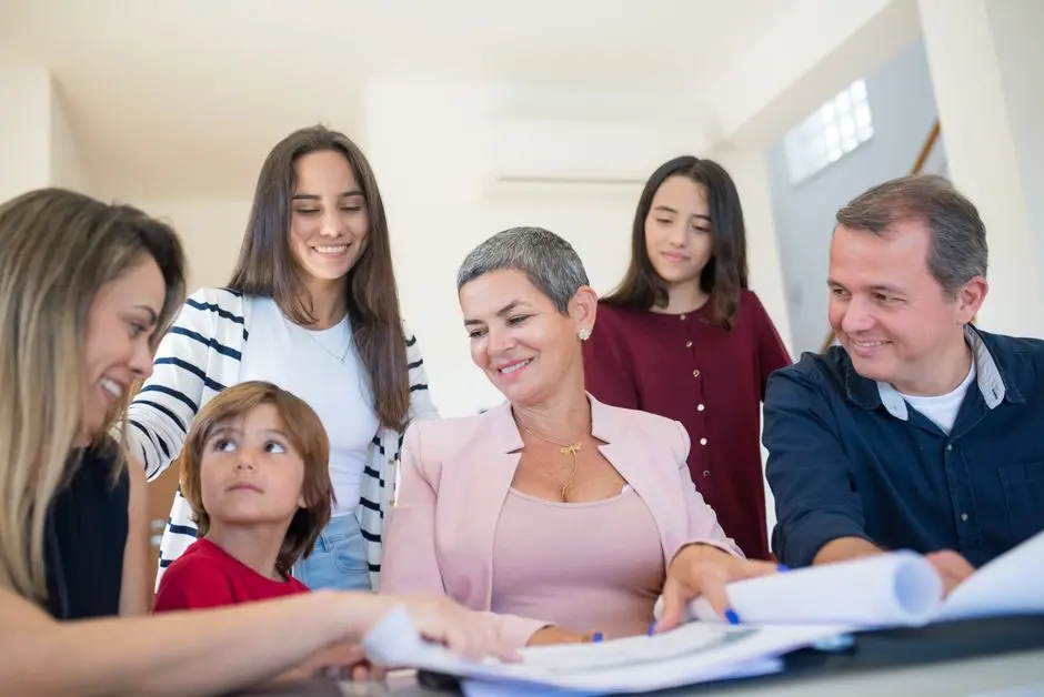 A family gathering around a table, discussing real estate documents indoors with a realtor.