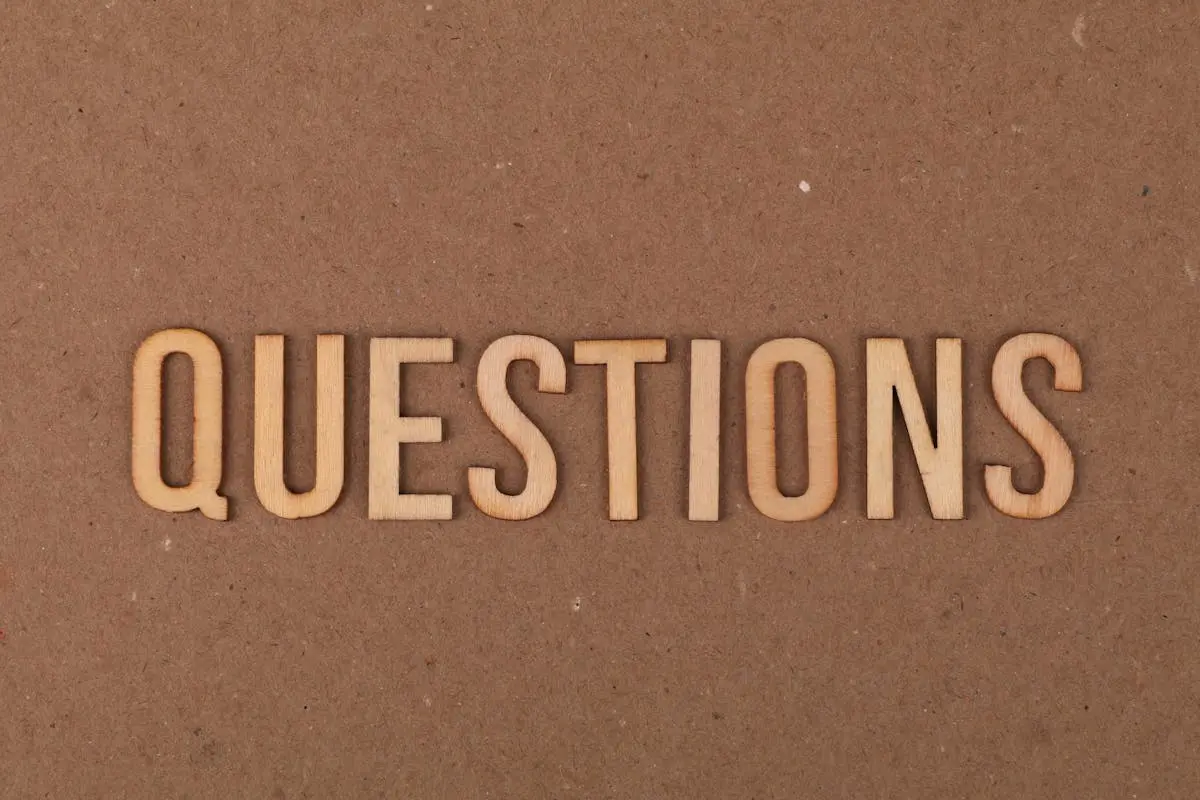 Wooden letters spelling the word “QUESTIONS” on a cardboard background, providing a neutral copyspace.