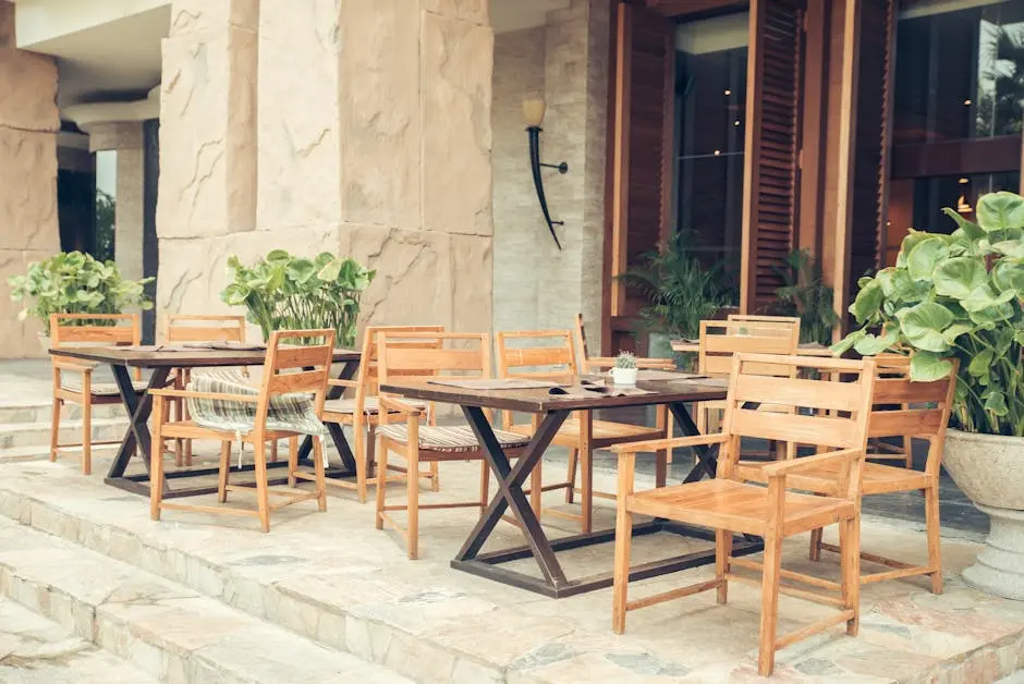 Elegant outdoor café area with wooden chairs and tables, decorated with lush greenery.