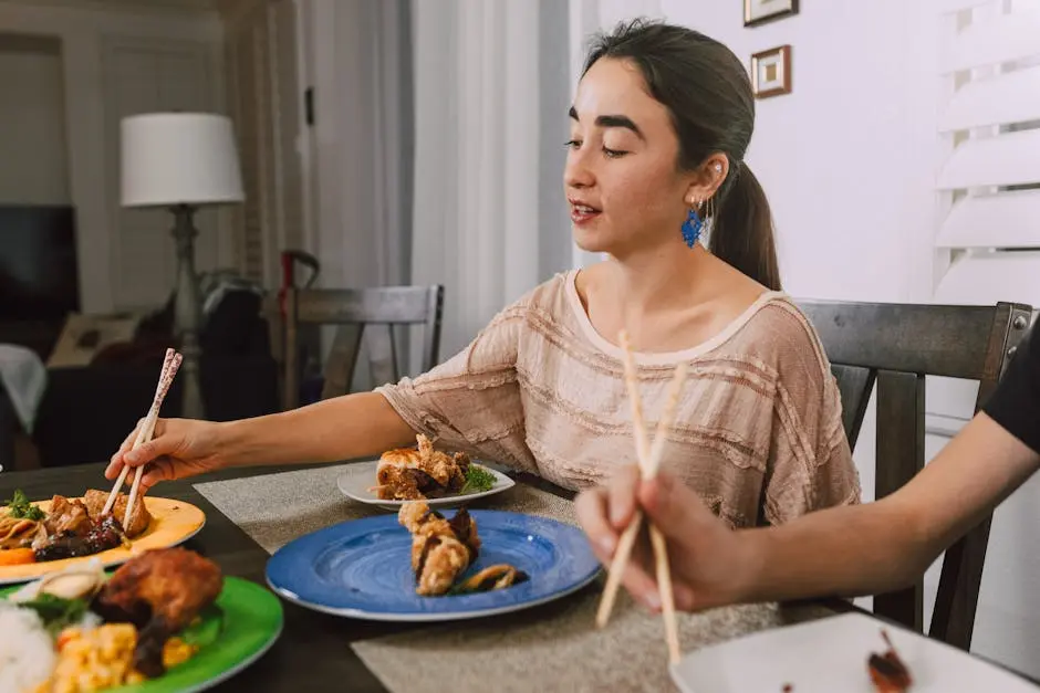 A woman and friends dining on a variety of Asian dishes indoors, using chopsticks.