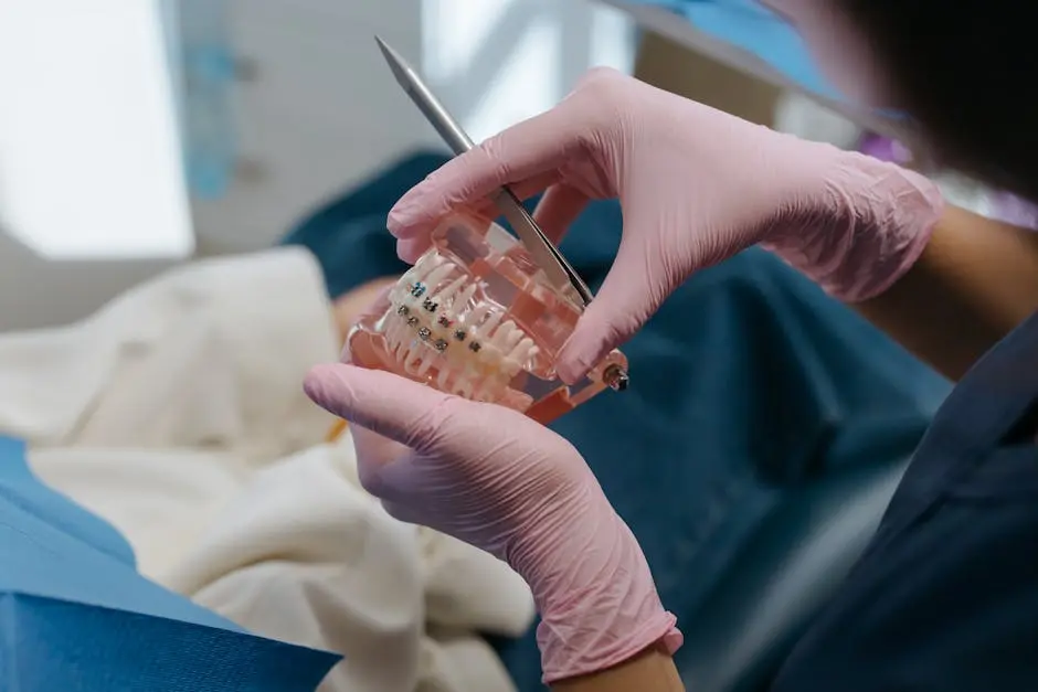 Close-up of a dental professional using tools on a teeth model with braces.