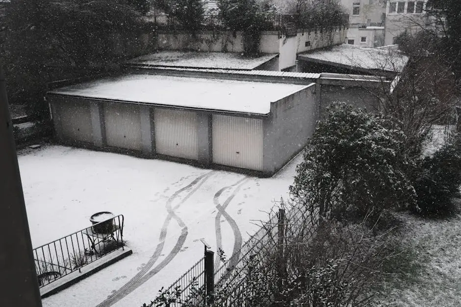 Aerial winter view of garages in a snowy urban area, showcasing fresh snowfall.