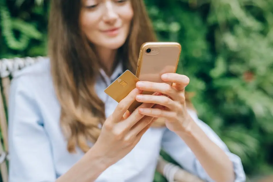 Woman using smartphone and credit card outdoors for online shopping.