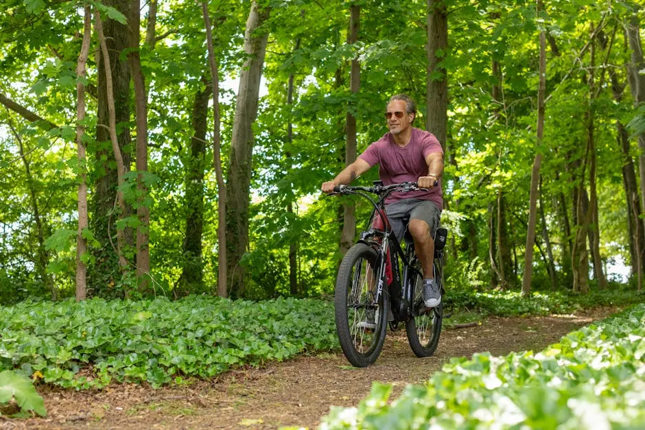 A man riding an electric bike on a forest trail during summer.