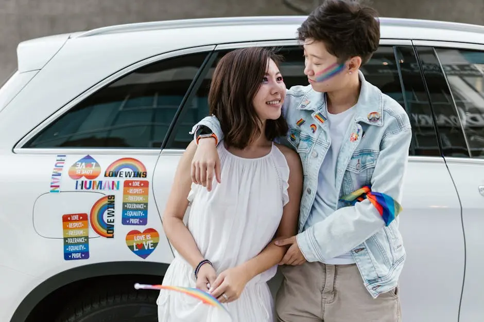 A joyful LGBTQ+ couple embracing near a car adorned with pride stickers, celebrating love and diversity.