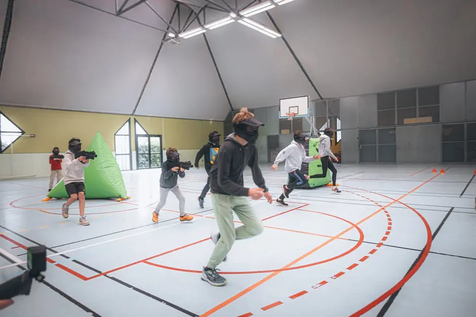 Energetic teenagers in action during an indoor laser tag game in a sports hall.