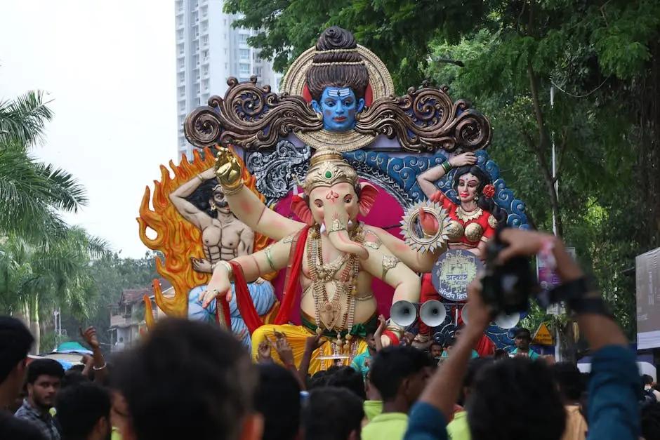 Colorful parade during Ganesh festival with large intricate statues and a crowd of onlookers.