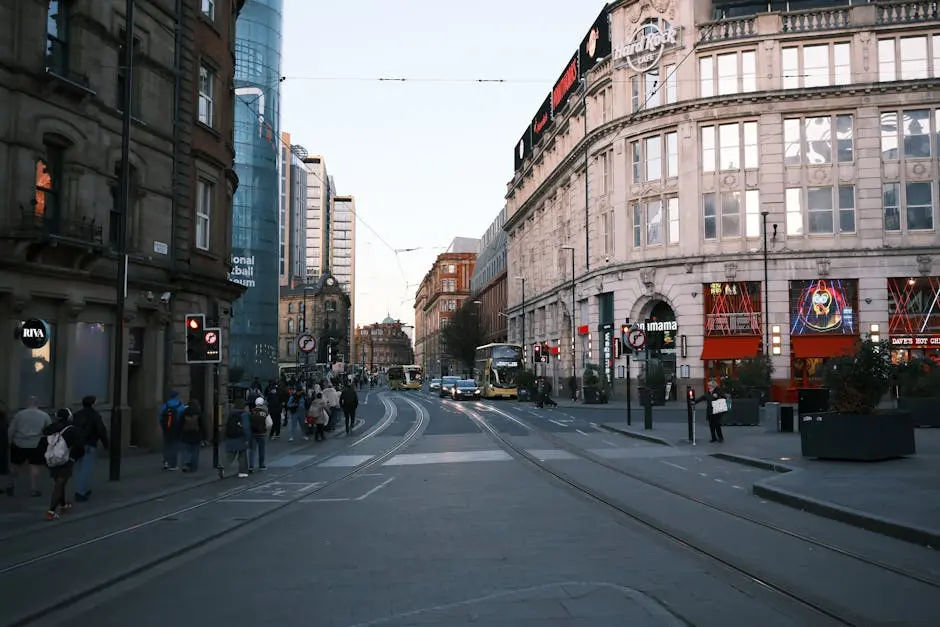 Evening scene of a busy street in Manchester with historic and modern architecture.