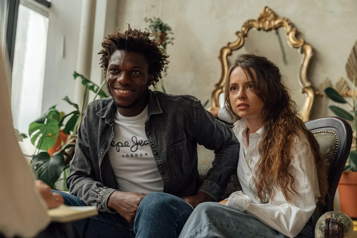 Couple engaged in therapy consultation, sitting on a sofa indoors.