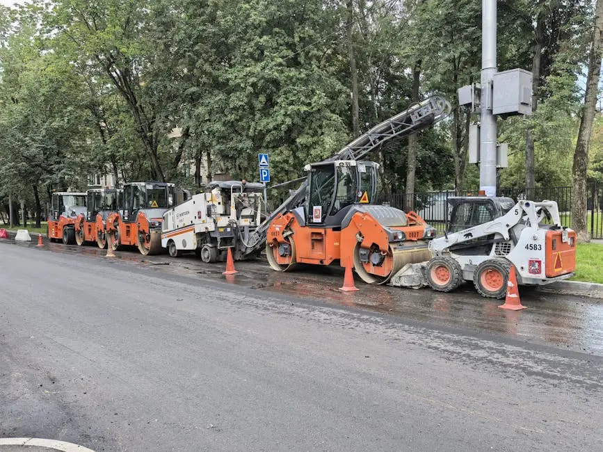 Heavy machinery lined up for road construction in a city.