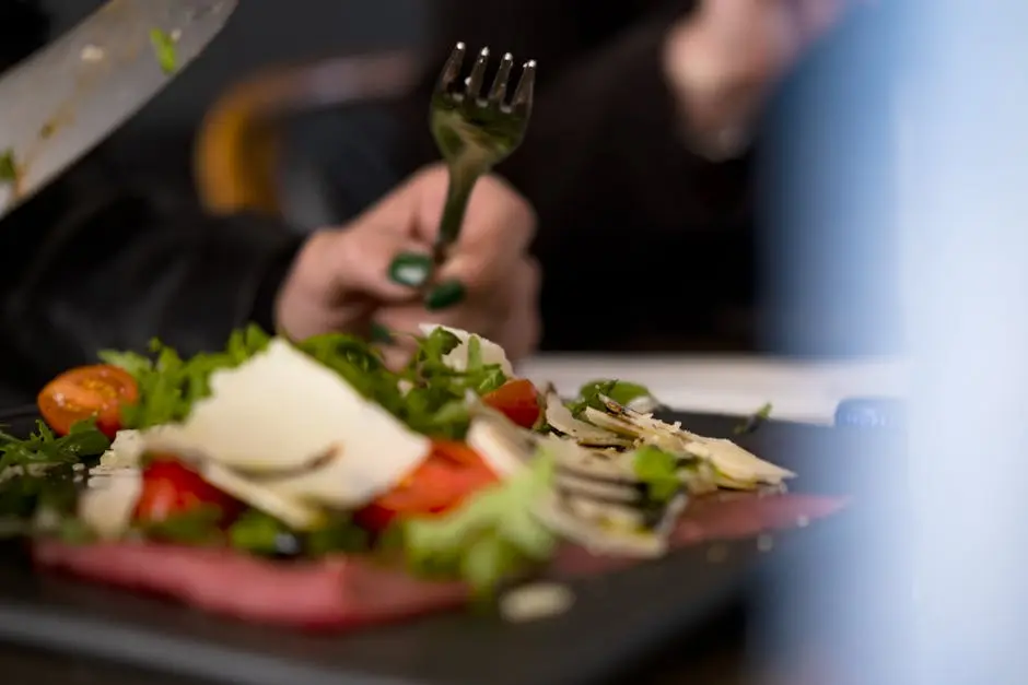 Close-up of a delicious Italian salad with cherry tomatoes, cheese shavings, and fresh greens served at a restaurant.