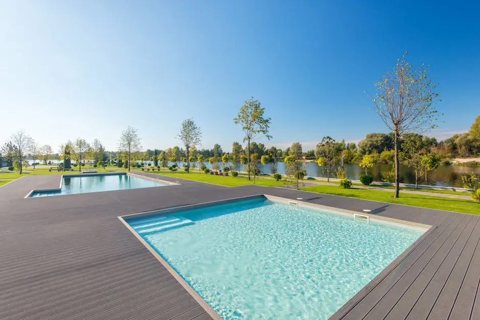 Relaxing poolside scene with a clear sky, lush trees, and a tranquil river backdrop.
