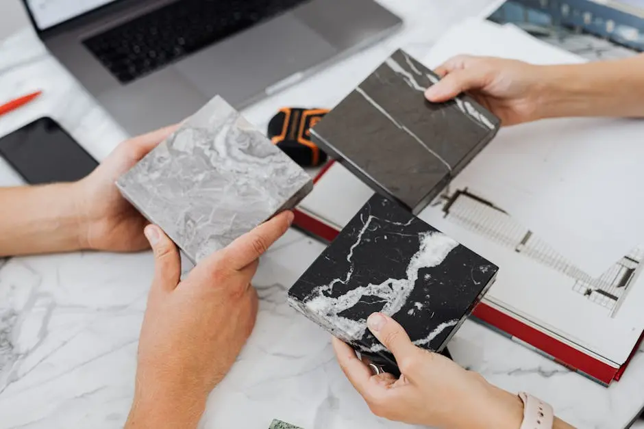 Two architects selecting marble tile samples on a desk in an office setting.