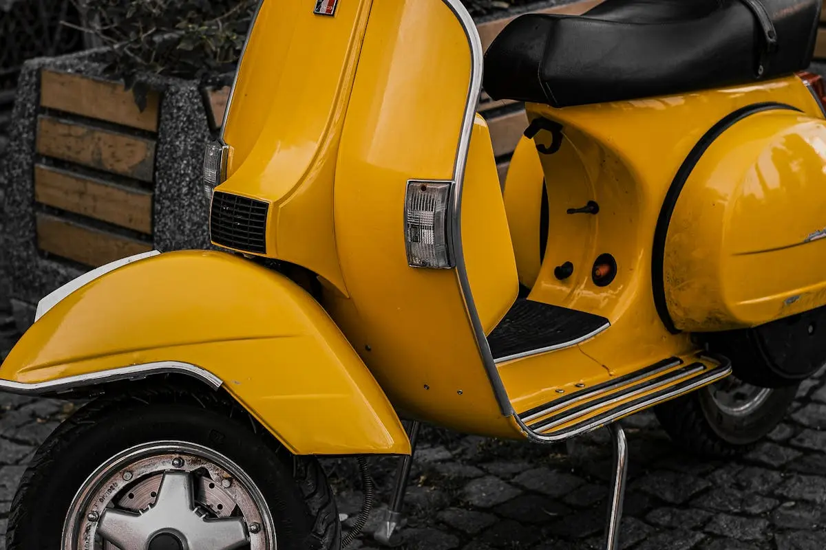 A classic yellow scooter parked on a cobblestone street in Bursa, Türkiye, exuding a nostalgic vibe.