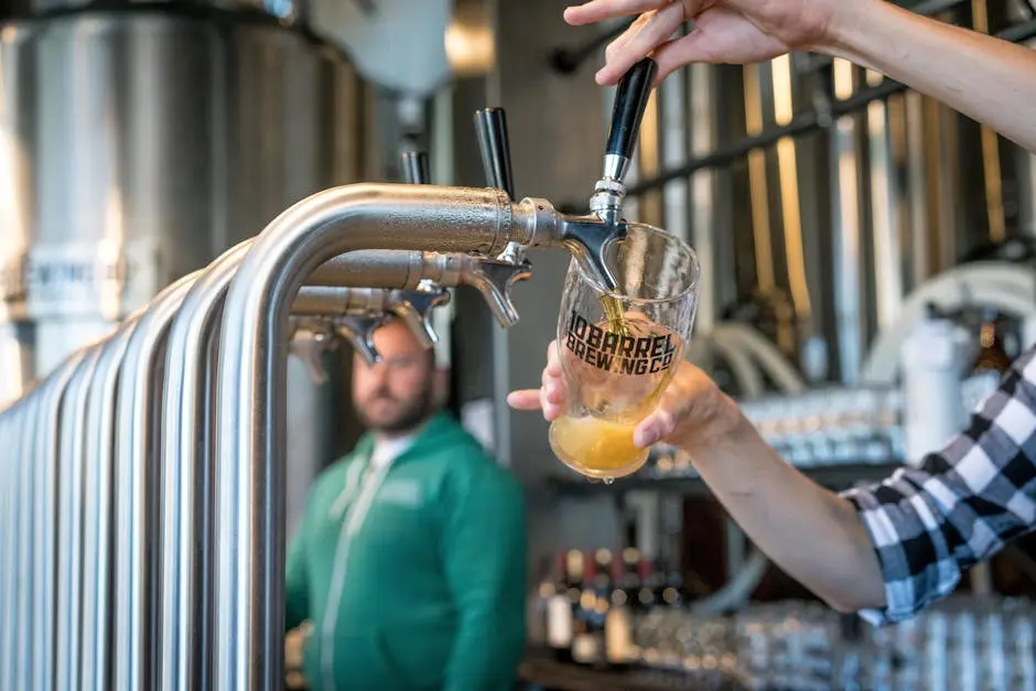 Close-up of beer being poured at a modern brewery taproom with bartender in background.